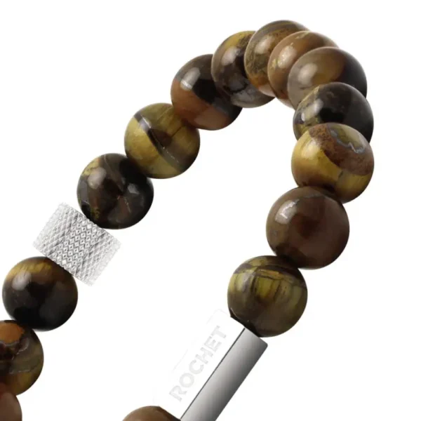 Rjava zapestnica iz sijočih okroglih kamnov (tigrovo oko) z elastičnim nizom in kovinskim detajlom z napisom “ROCHET”.